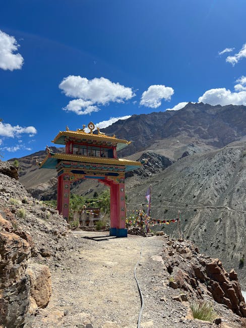 pexels-photo-17905659-17905659 Colorful entrance gate to Phugtal Monastery set against rugged Himalayas under a clear blue sky.