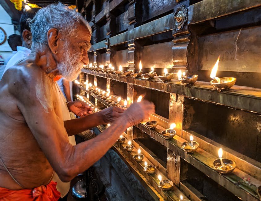 pexels-photo-977530-977530 An elderly man lighting traditional oil lamps inside a temple, creating a serene ambiance.